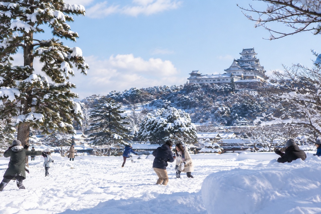 日本で人々がいる中雪を触る若夫婦