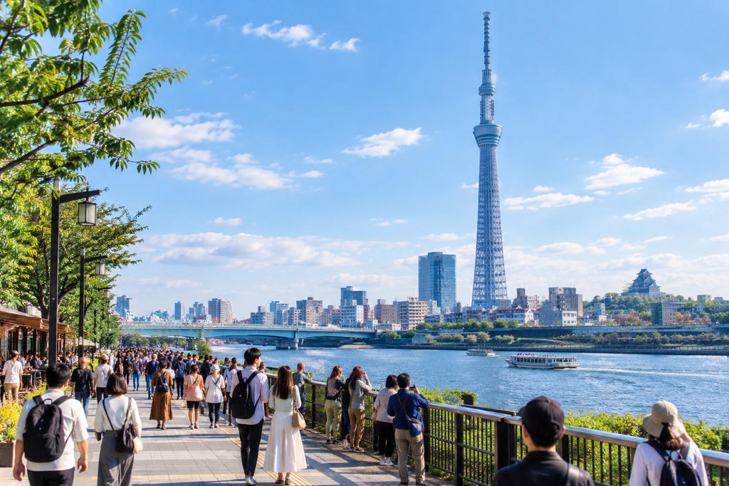 日本で人々がいる中スカイツリーを見上げる若夫婦