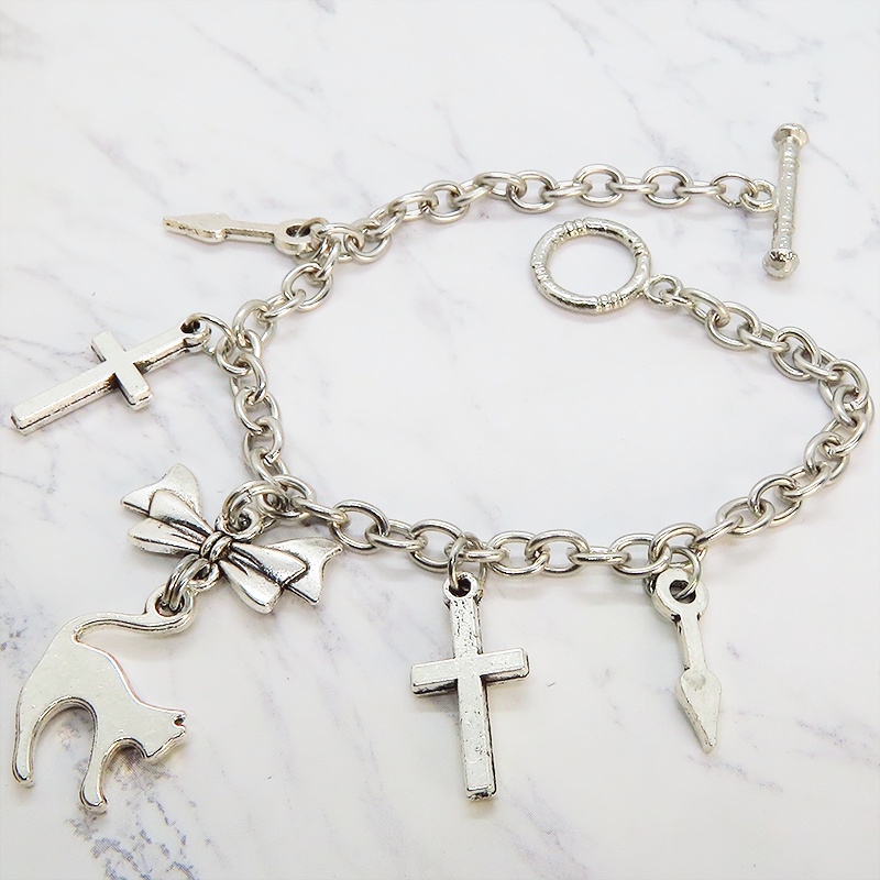 シルバーカラー 猫シルエットモチーフとリボンにロザリオと時計の針が連なるブレスレット