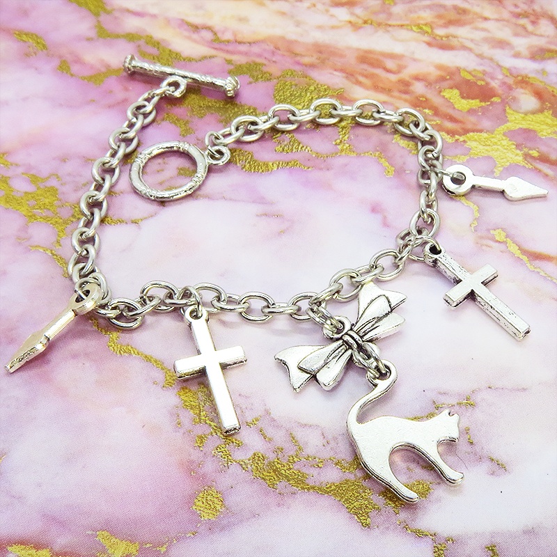 シルバーカラー 猫シルエットモチーフとリボンにロザリオと時計の針が連なるブレスレット