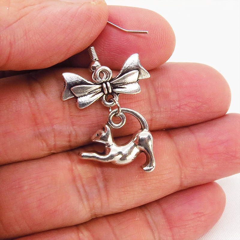 アンティークシルバー のび猫シルエットモチーフとリボンを組合せたコンパクトなピアス サージカル可