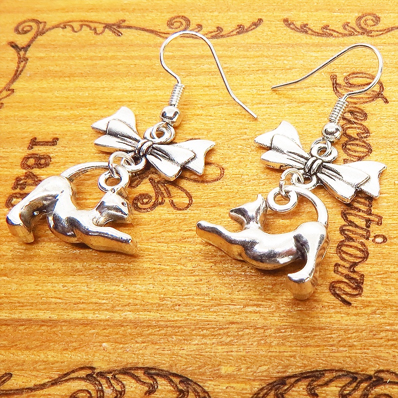 アンティークシルバー のび猫シルエットモチーフとリボンを組合せたコンパクトなピアス サージカル可