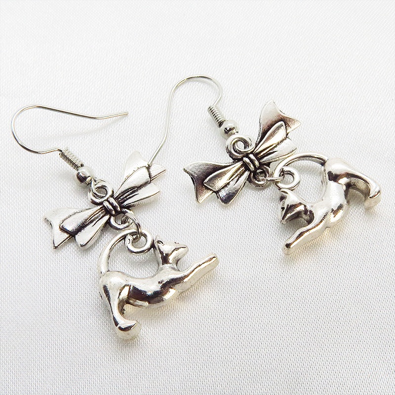 アンティークシルバー のび猫シルエットモチーフとリボンを組合せたコンパクトなピアス サージカル可
