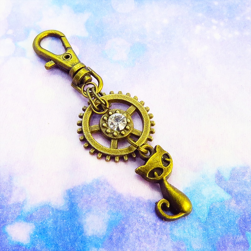 アンティークゴールド 猫と歯車を組合せた可愛いキーホルダー スワロフスキー・クリスタル バッグチャーム ファスナーチャーム