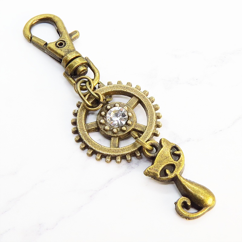 アンティークゴールド 猫と歯車を組合せた可愛いキーホルダー スワロフスキー・クリスタル バッグチャーム ファスナーチャーム