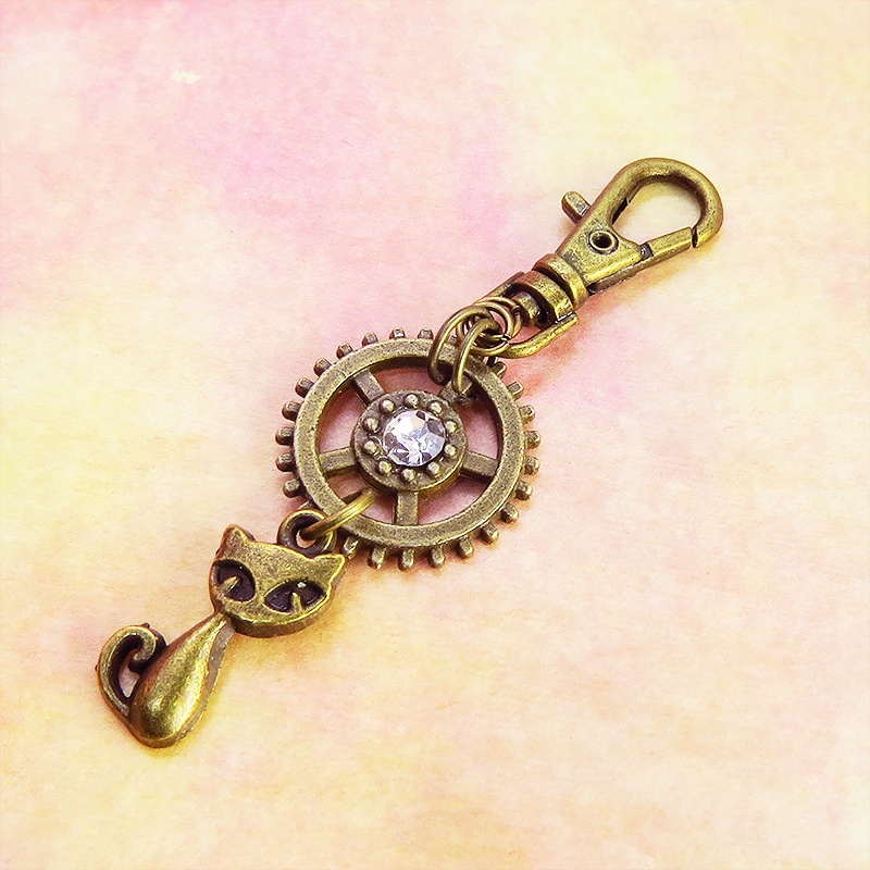 アンティークゴールド 猫と歯車を組合せた可愛いキーホルダー スワロフスキー・クリスタル バッグチャーム ファスナーチャーム