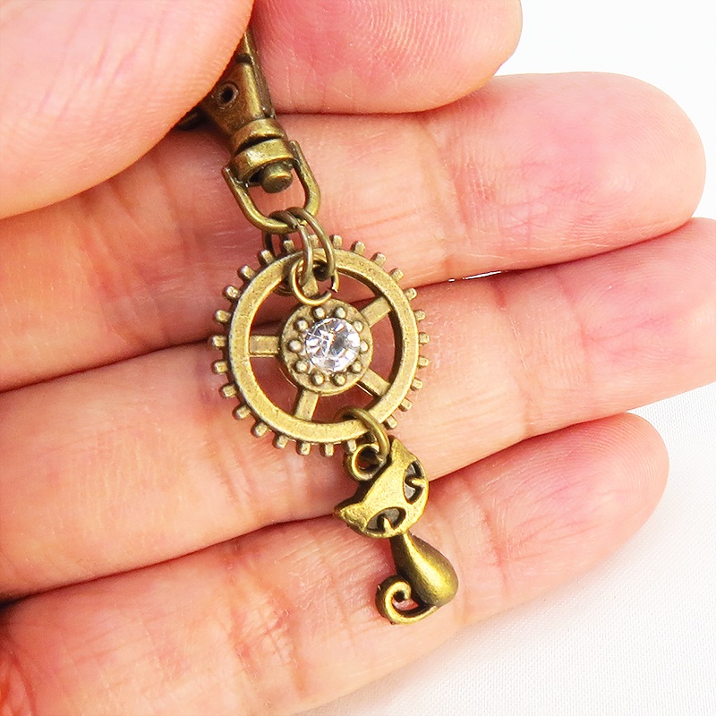 アンティークゴールド 猫と歯車を組合せた可愛いキーホルダー スワロフスキー・クリスタル バッグチャーム ファスナーチャーム