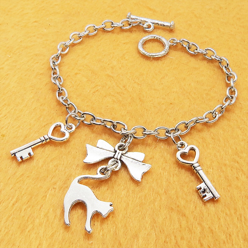 アンティークシルバー 跳ね猫シルエットモチーフとリボンに鍵が連なるブレスレット