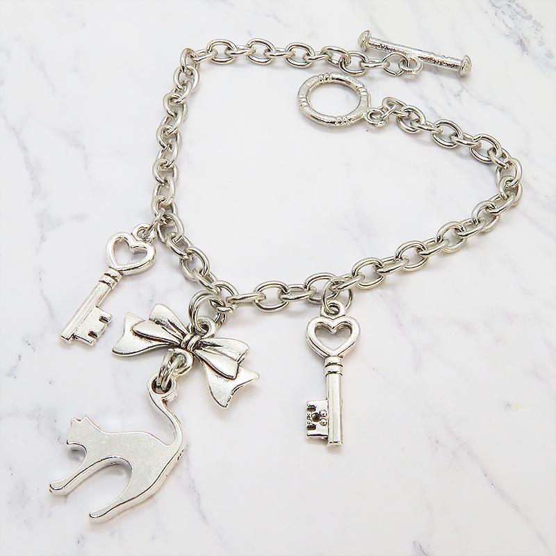 アンティークシルバー 跳ね猫シルエットモチーフとリボンに鍵が連なるブレスレット