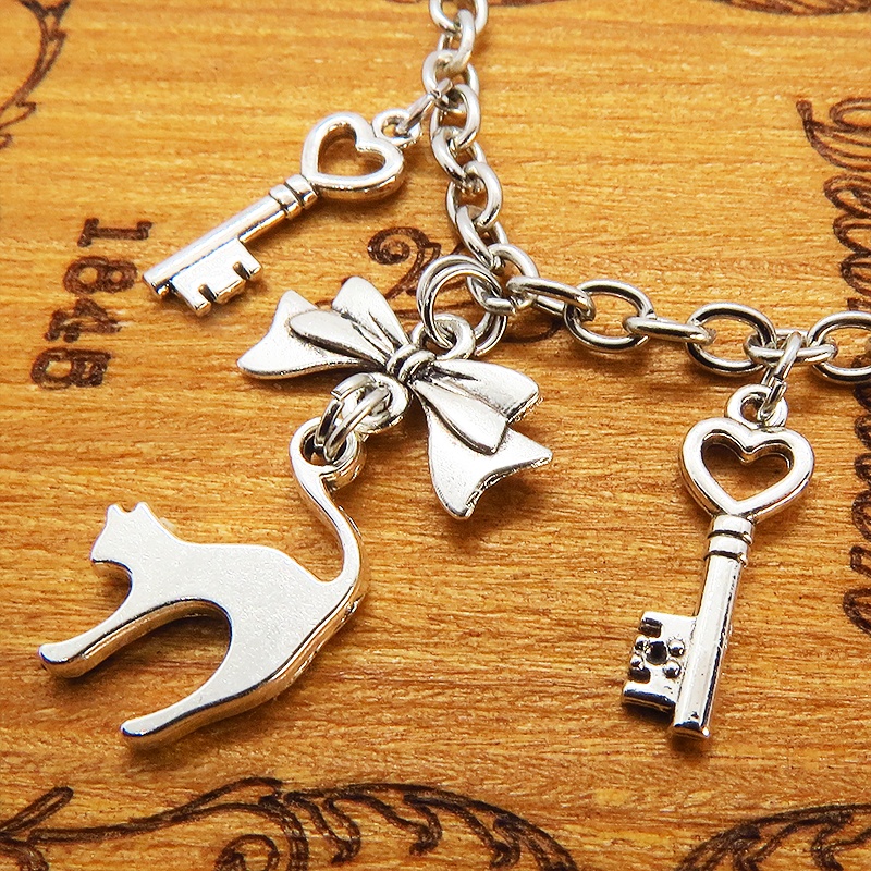 アンティークシルバー 跳ね猫シルエットモチーフとリボンに鍵が連なるブレスレット