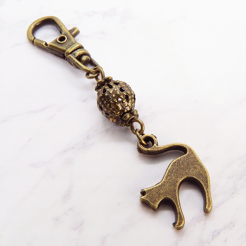 アンティークカラーの跳ね猫モチーフと透かしメタルビーズのファスナーチャーム キーホルダー
