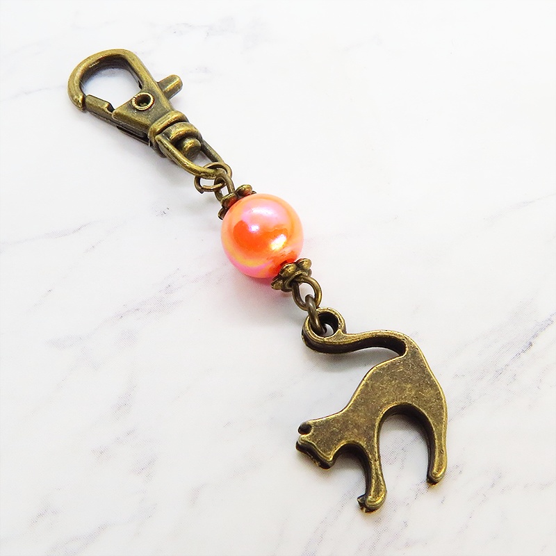 アンティークカラーの跳ね猫モチーフとオレンジミックスビーズのファスナーチャーム キーホルダー