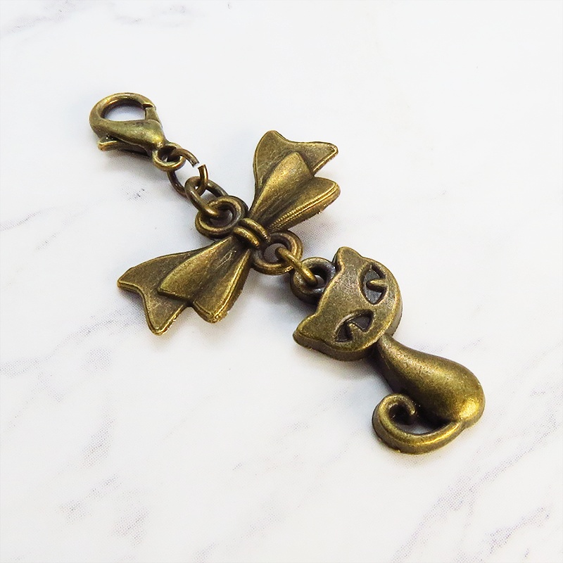 マスク・スマホチャーム アンティークゴールド 猫モチーフとリボンのコンパクトで可愛いチャーム ジャックピン追加可