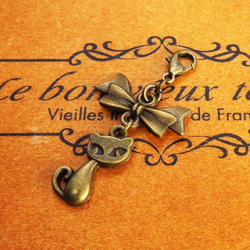 マスク・スマホチャーム アンティークゴールド 猫モチーフとリボンのコンパクトで可愛いチャーム ジャックピン追加可