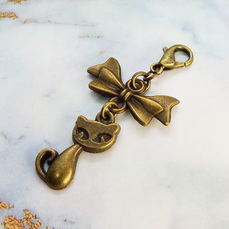 マスク・スマホチャーム アンティークゴールド 猫モチーフとリボンのコンパクトで可愛いチャーム ジャックピン追加可