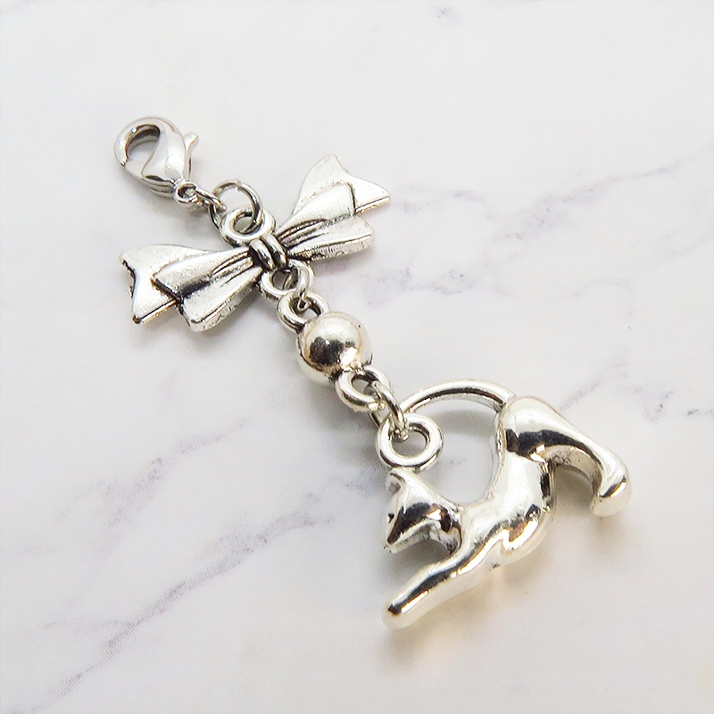 のび猫をかたどったシルエットモチーフとリボンの可愛いマスクチャーム アンティークシルバー