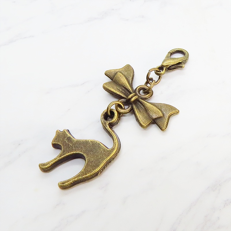 マスクチャーム アンティークカラー(金古美色)の跳ね猫とリボンの大人可愛いチャーム キーホルダー