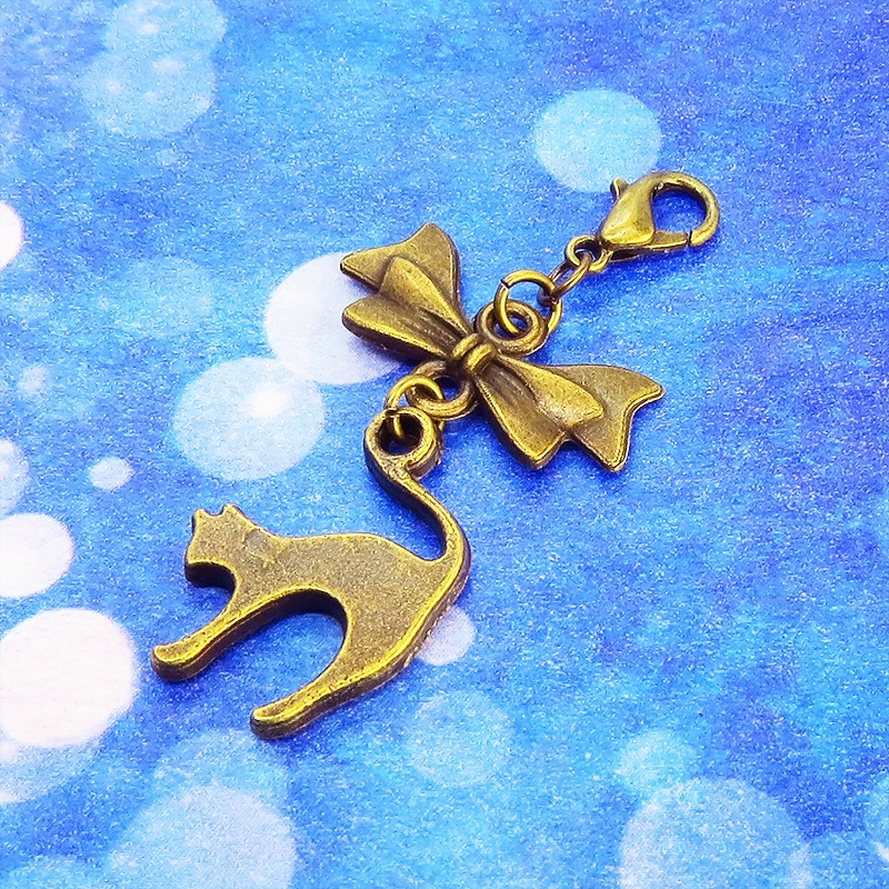 マスクチャーム アンティークカラー(金古美色)の跳ね猫とリボンの大人可愛いチャーム キーホルダー