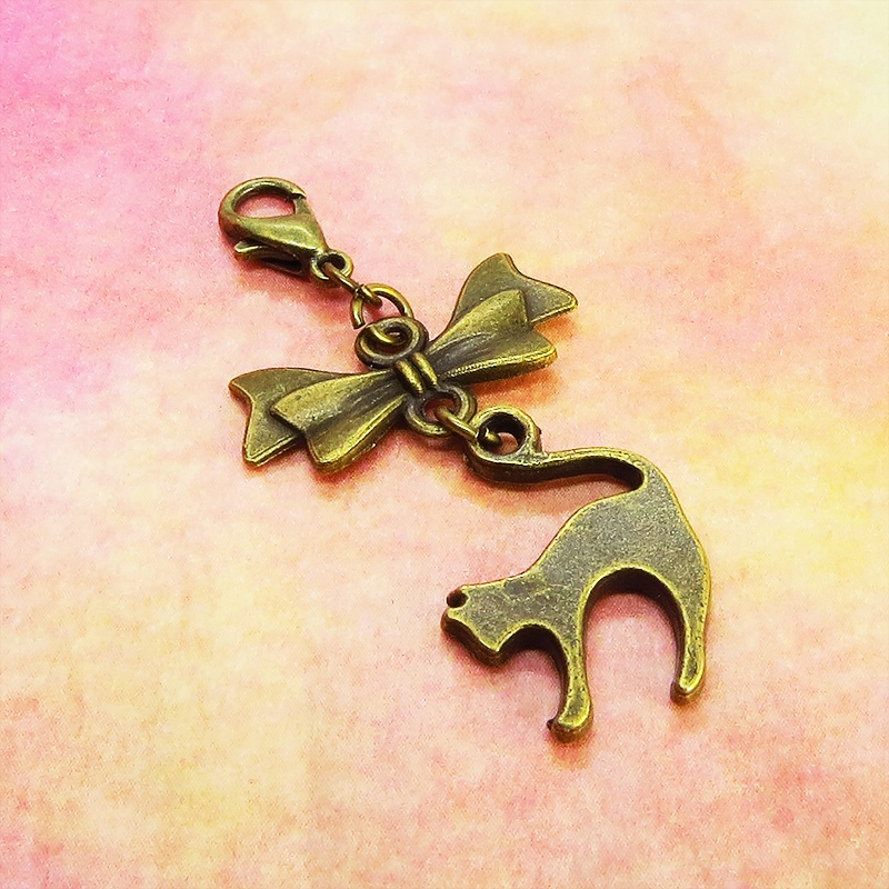 マスクチャーム アンティークカラー(金古美色)の跳ね猫とリボンの大人可愛いチャーム キーホルダー