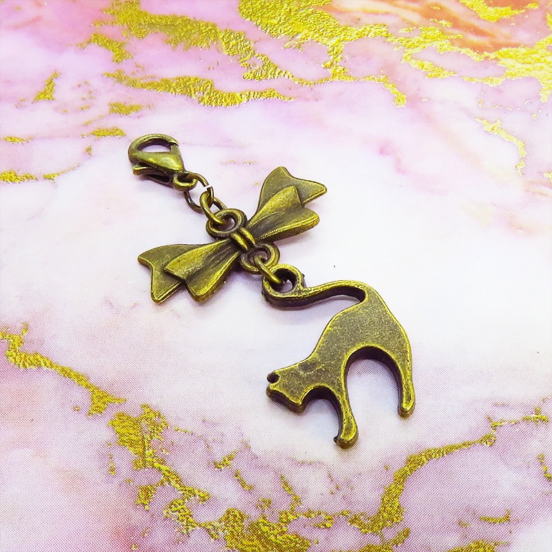 マスクチャーム アンティークカラー(金古美色)の跳ね猫とリボンの大人可愛いチャーム キーホルダー