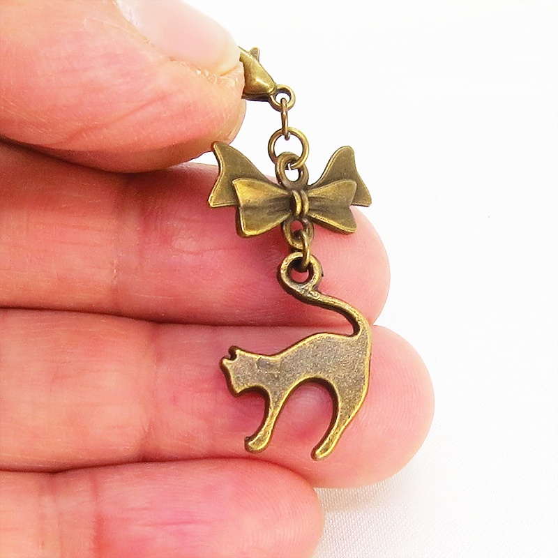 マスクチャーム アンティークカラー(金古美色)の跳ね猫とリボンの大人可愛いチャーム キーホルダー