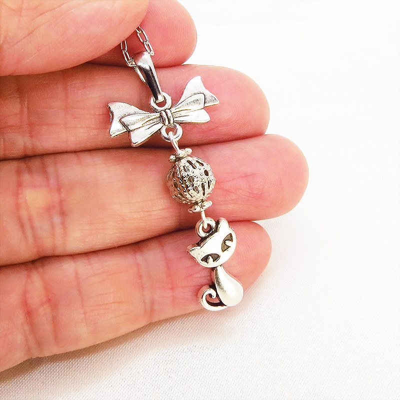 アンティークシルバーの猫とリボンと透かしメタルビーズのチャームのネックレス