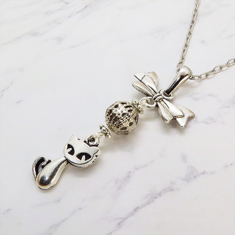 アンティークシルバーの猫とリボンと透かしメタルビーズのチャームのネックレス