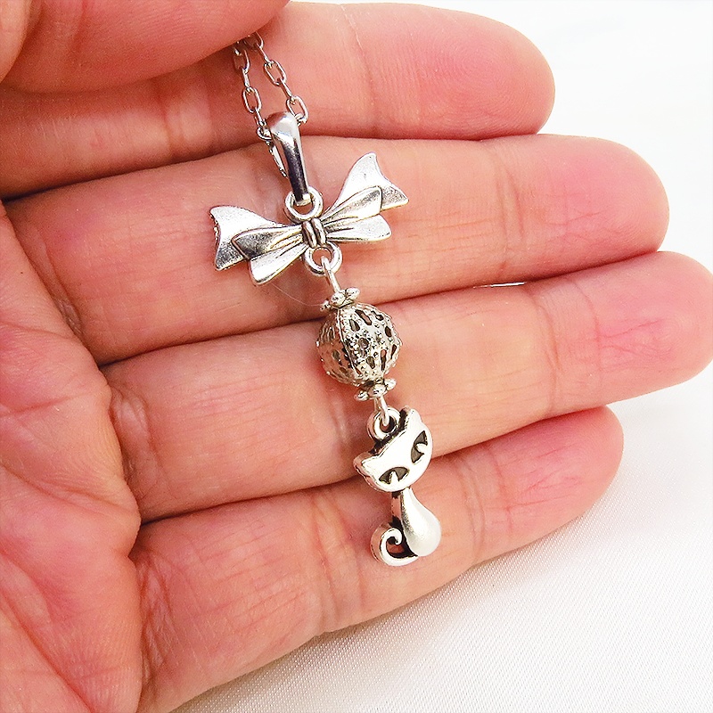 アンティークシルバーの猫とリボンと透かしメタルビーズのチャームのネックレス