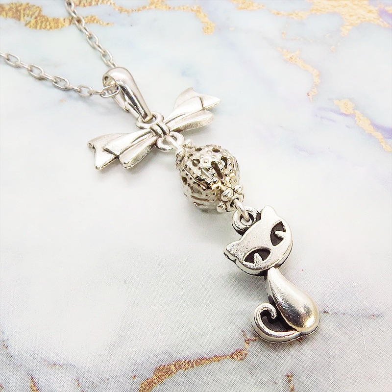 アンティークシルバーの猫とリボンと透かしメタルビーズのチャームのネックレス