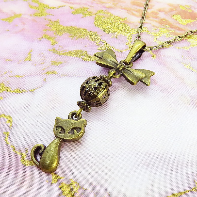 アンティークカラーの猫とリボンと透かしメタルビーズのチャームのネックレス