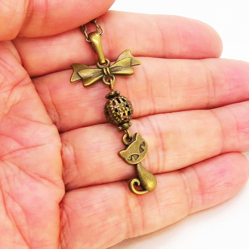 アンティークカラーの猫とリボンと透かしメタルビーズのチャームのネックレス