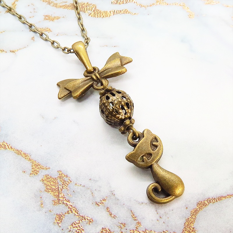 アンティークカラーの猫とリボンと透かしメタルビーズのチャームのネックレス