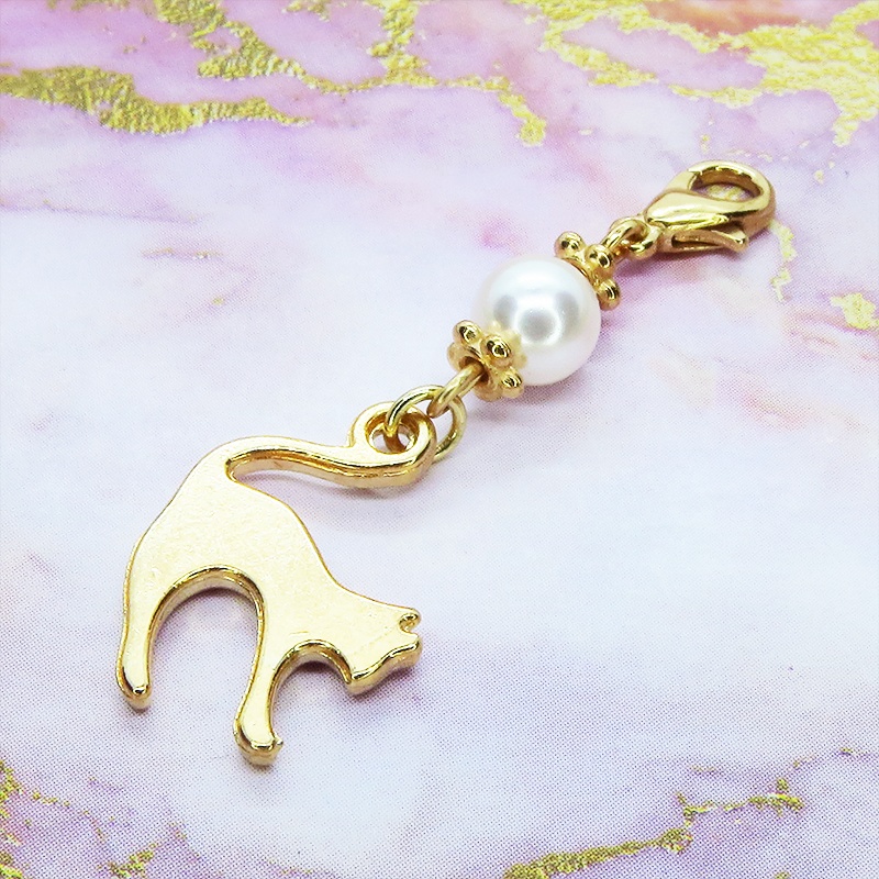 マスクチャーム マットゴールドの跳ね猫モチーフとスワロフスキーパール(クリスタルホワイト)のチャーム キーホルダー