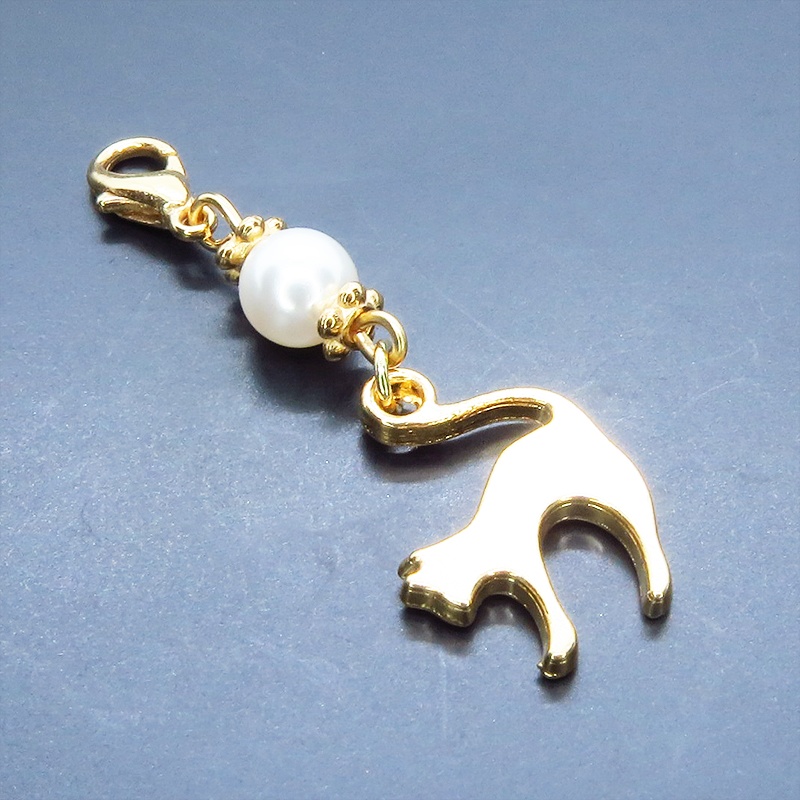 マスクチャーム マットゴールドの跳ね猫モチーフとスワロフスキーパール(クリスタルホワイト)のチャーム キーホルダー