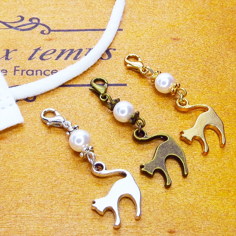 マスクチャーム アンティークカラーの跳ね猫モチーフとスワロフスキーパール(クリスタルホワイト)のチャーム キーホルダー