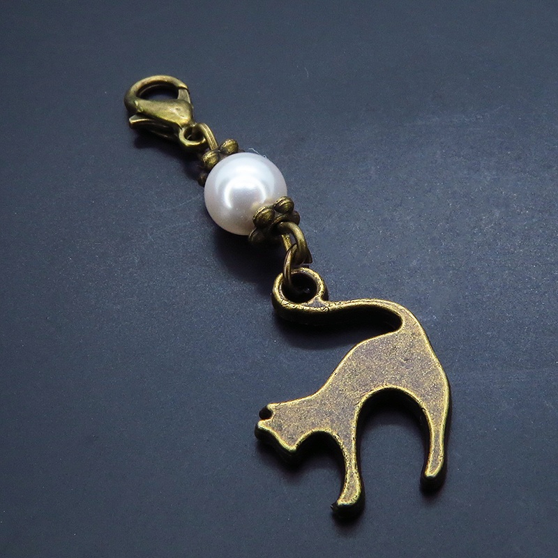 マスクチャーム アンティークカラーの跳ね猫モチーフとスワロフスキーパール(クリスタルホワイト)のチャーム キーホルダー