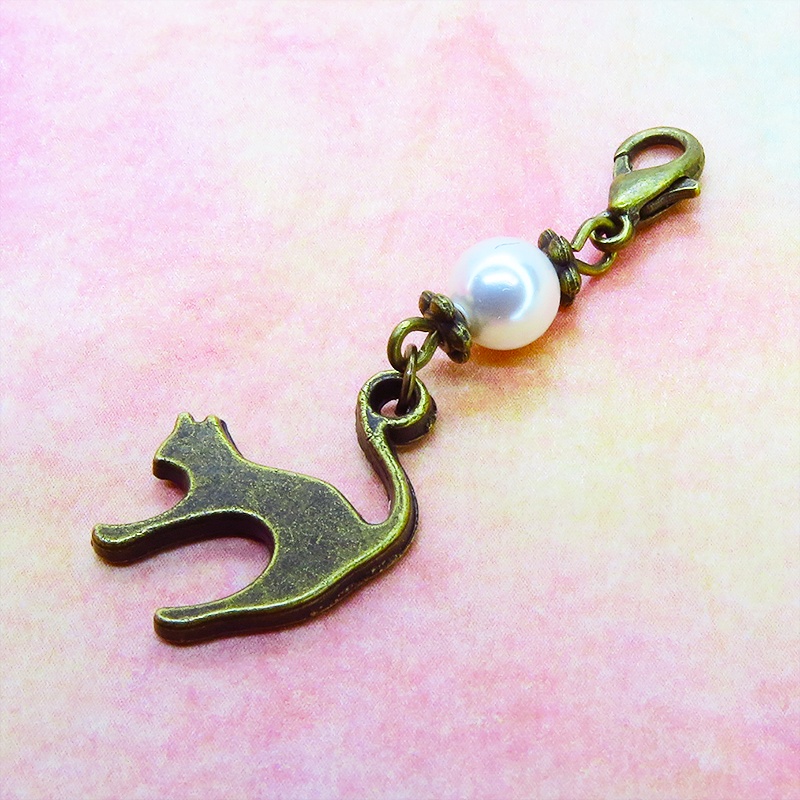マスクチャーム アンティークカラーの跳ね猫モチーフとスワロフスキーパール(クリスタルホワイト)のチャーム キーホルダー