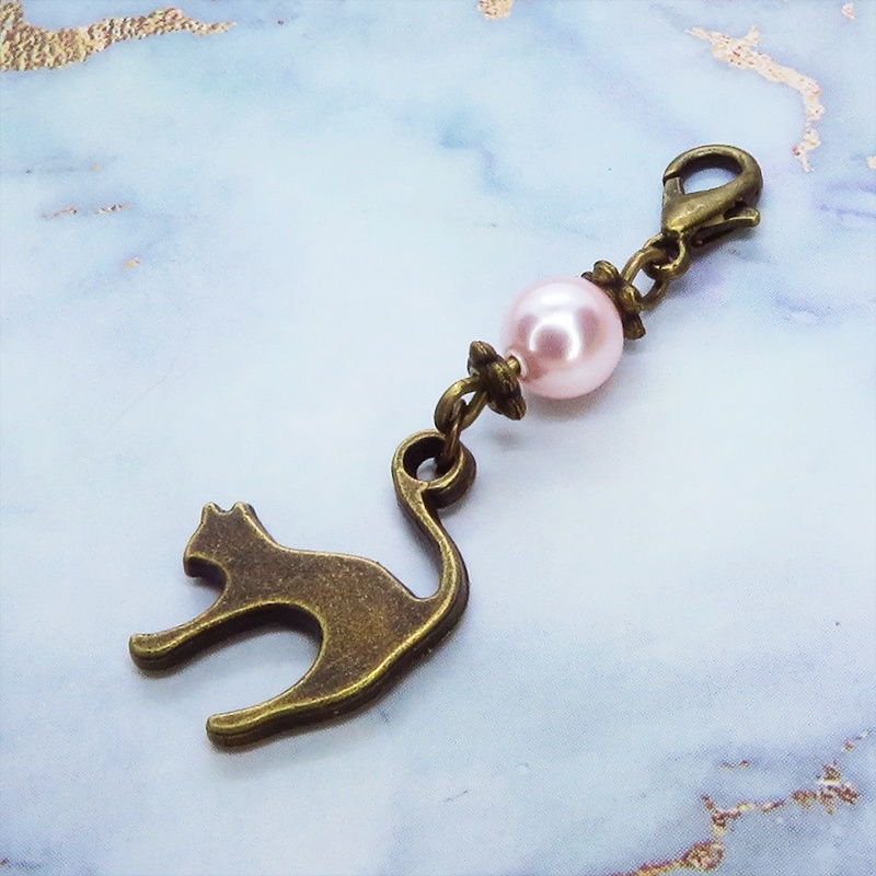 マスクチャーム アンティークカラーの跳ね猫モチーフとスワロフスキーパール(ロザリン)のチャーム キーホルダー