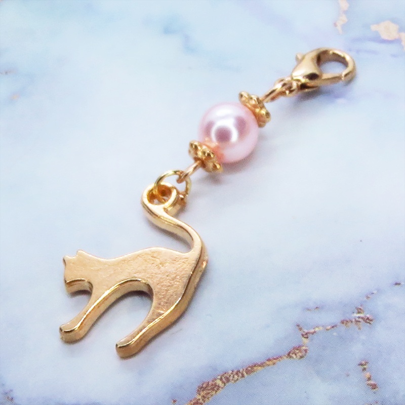 マスクチャーム マットゴールドの跳ね猫モチーフとスワロフスキーパール(ロザリン)のチャーム キーホルダー