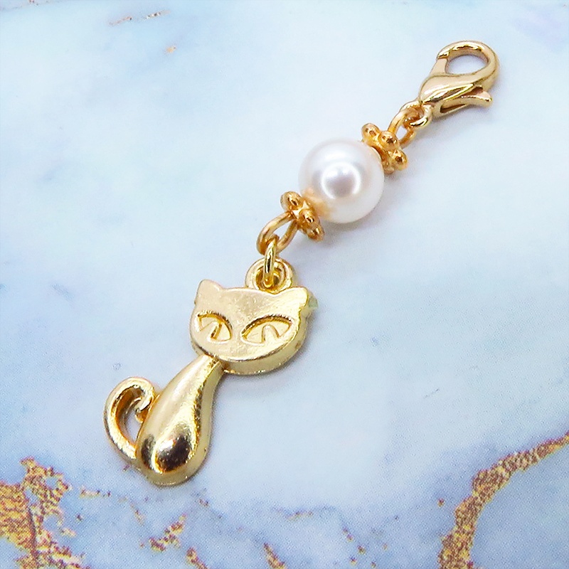 マスクチャーム マットゴールドの猫モチーフとスワロフスキーパール(クリスタルホワイト)のチャーム キーホルダー
