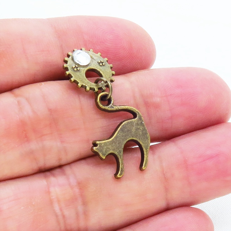 アンティークゴールドの跳ね猫モチーフと歯車のスチームパンク風スタッドピアス クリスタルガラス