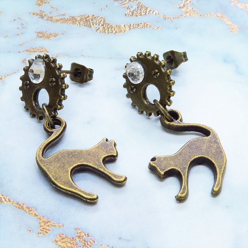アンティークゴールドの跳ね猫モチーフと歯車のスチームパンク風スタッドピアス クリスタルガラス