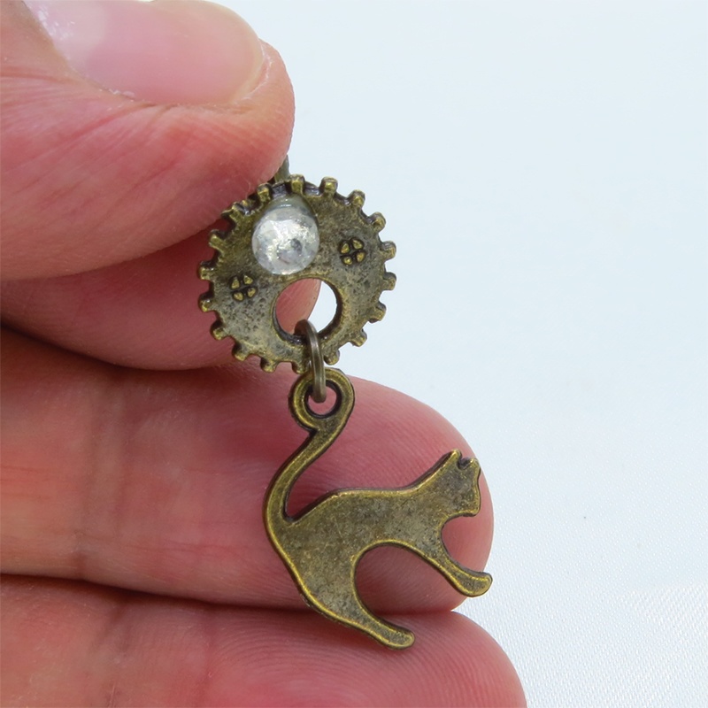 アンティークゴールドの跳ね猫モチーフと歯車のスチームパンク風スタッドピアス クリスタルガラス