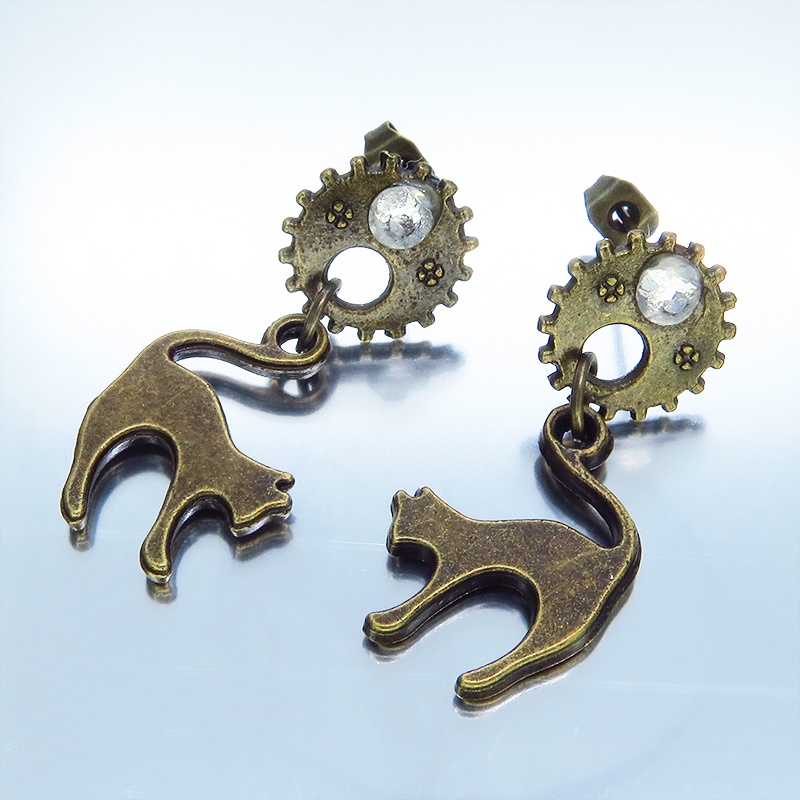 アンティークゴールドの跳ね猫モチーフと歯車のスチームパンク風スタッドピアス クリスタルガラス
