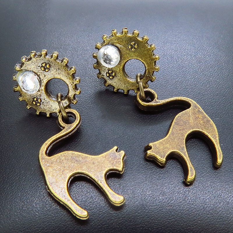 アンティークゴールドの跳ね猫モチーフと歯車のスチームパンク風スタッドピアス クリスタルガラス