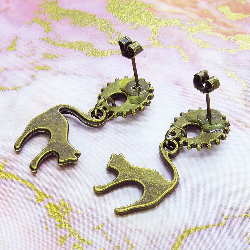 アンティークゴールドの跳ね猫モチーフと歯車のスチームパンク風スタッドピアス クリスタルガラス