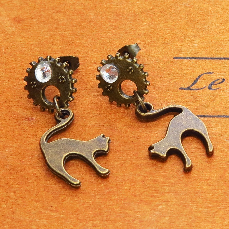 アンティークゴールドの跳ね猫モチーフと歯車のスチームパンク風スタッドピアス クリスタルガラス