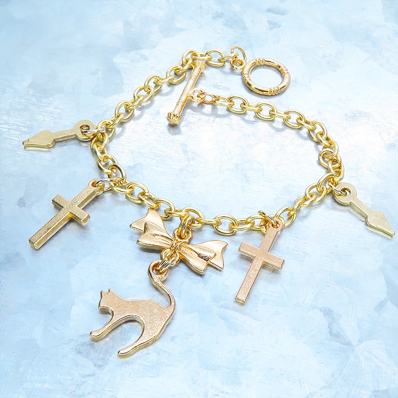 マットゴールドの猫シルエットモチーフとリボンに鍵と時計の針が連なるブレスレット