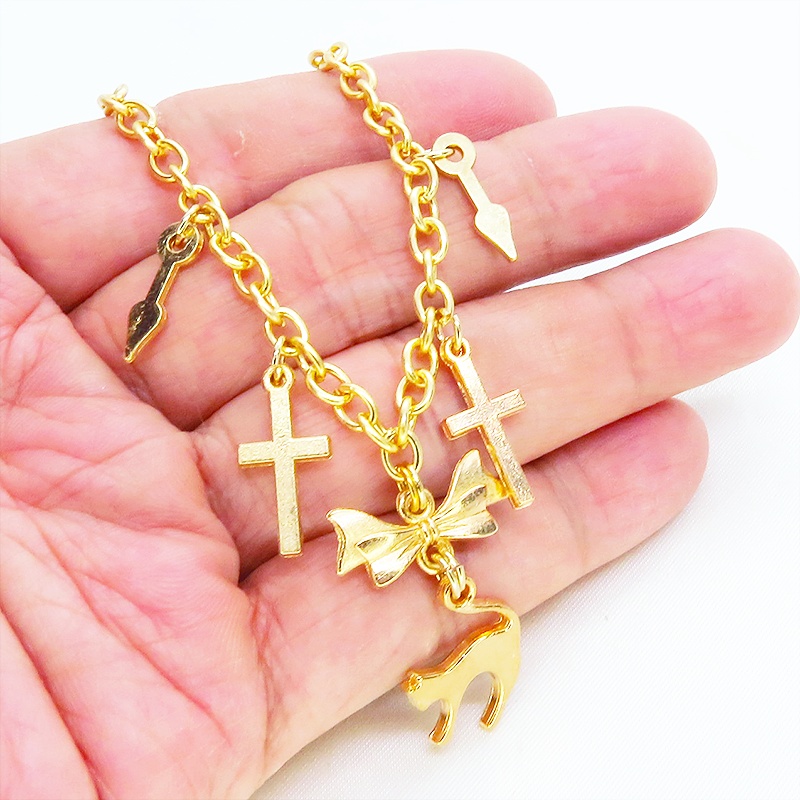 マットゴールドの猫シルエットモチーフとリボンに鍵と時計の針が連なるブレスレット