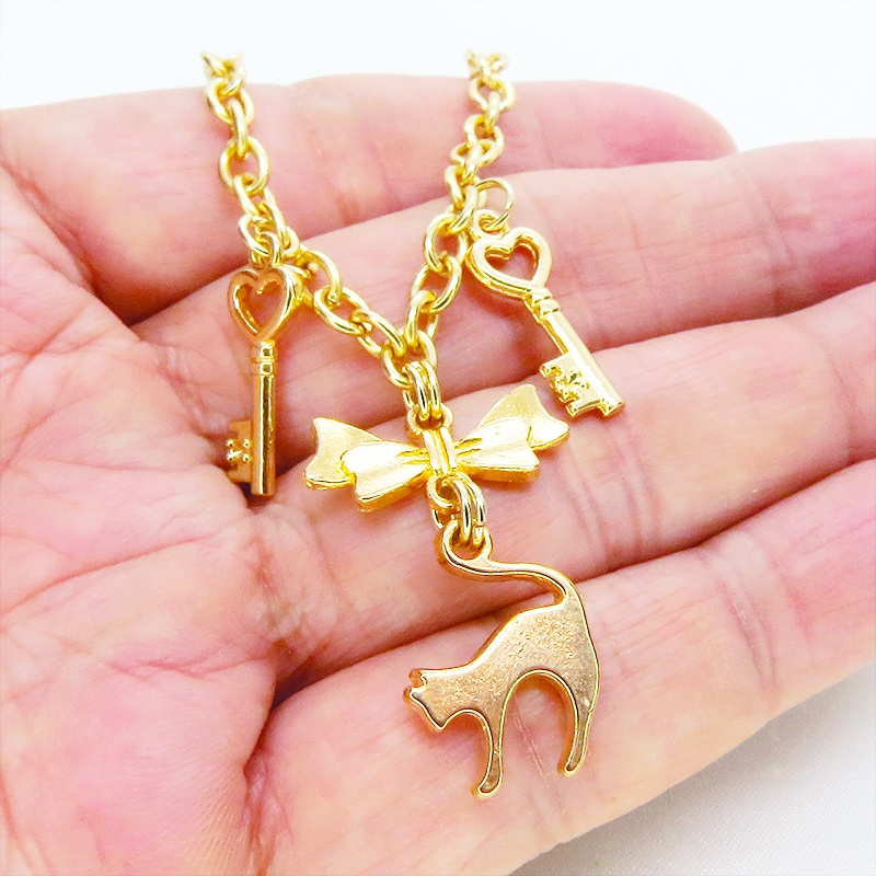 マットゴールドの跳ね猫シルエットモチーフとリボンに鍵が連なるブレスレット